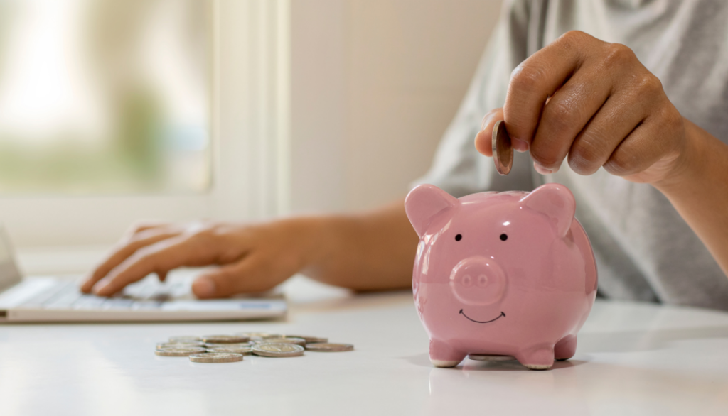 This is an image of someone putting coins into piggy bank.