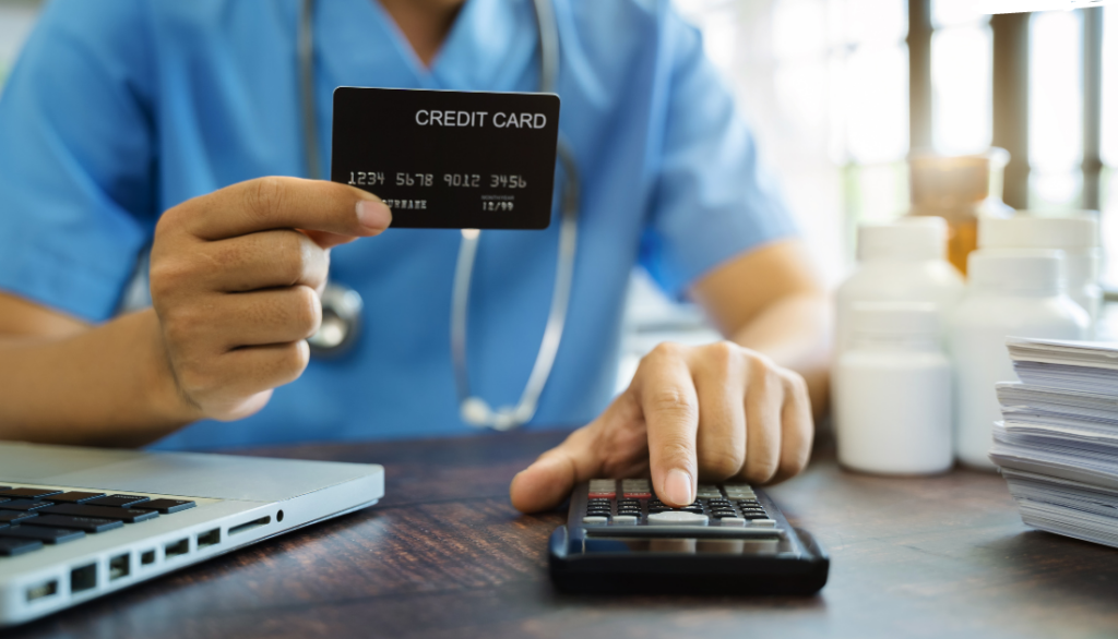 This is a doctor holding a credit card and using a calculator.