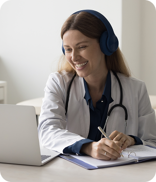 A doctor smiling at a screen while taking notes