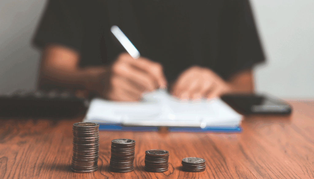 This is a person writing on paper with money in front of them.