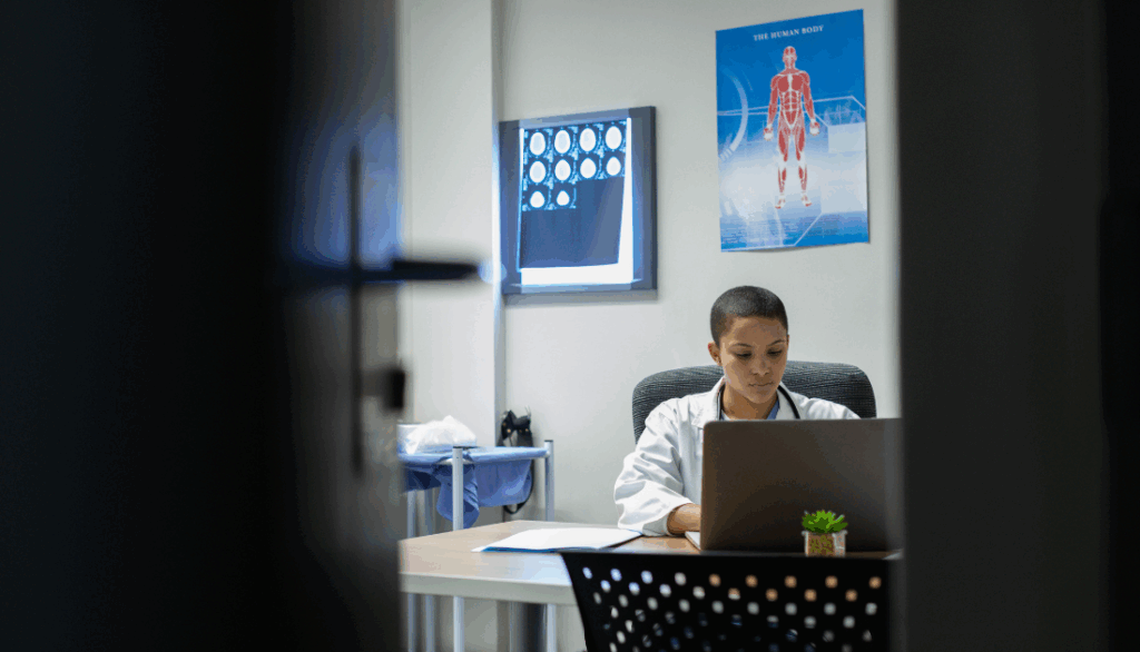 A doctor sitting at a desk looking at computer.