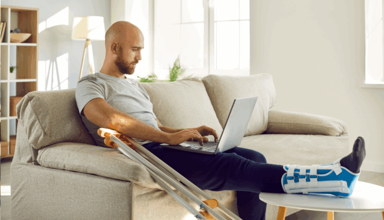 A man with an ankle brace looking at a laptop