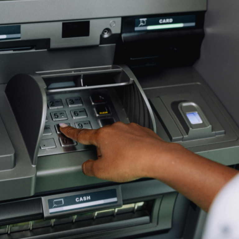 This is an image of a person pushing keys on an ATM.