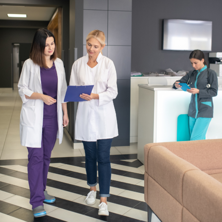 This is a photo of two female doctors looking at a clipboard.