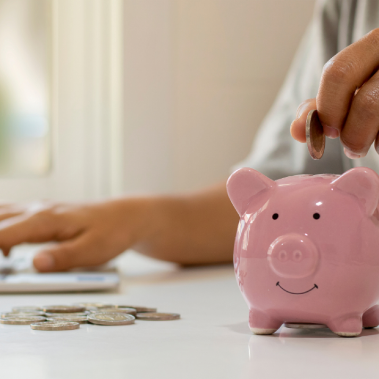 This is an image of someone putting coins into piggy bank.