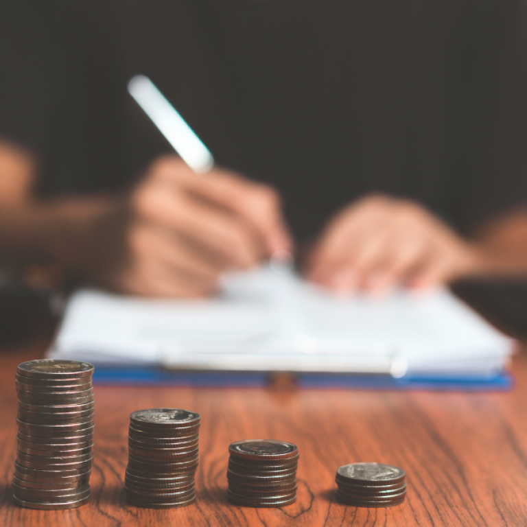 Article Image (68) This is a person writing on paper with money in front of them.